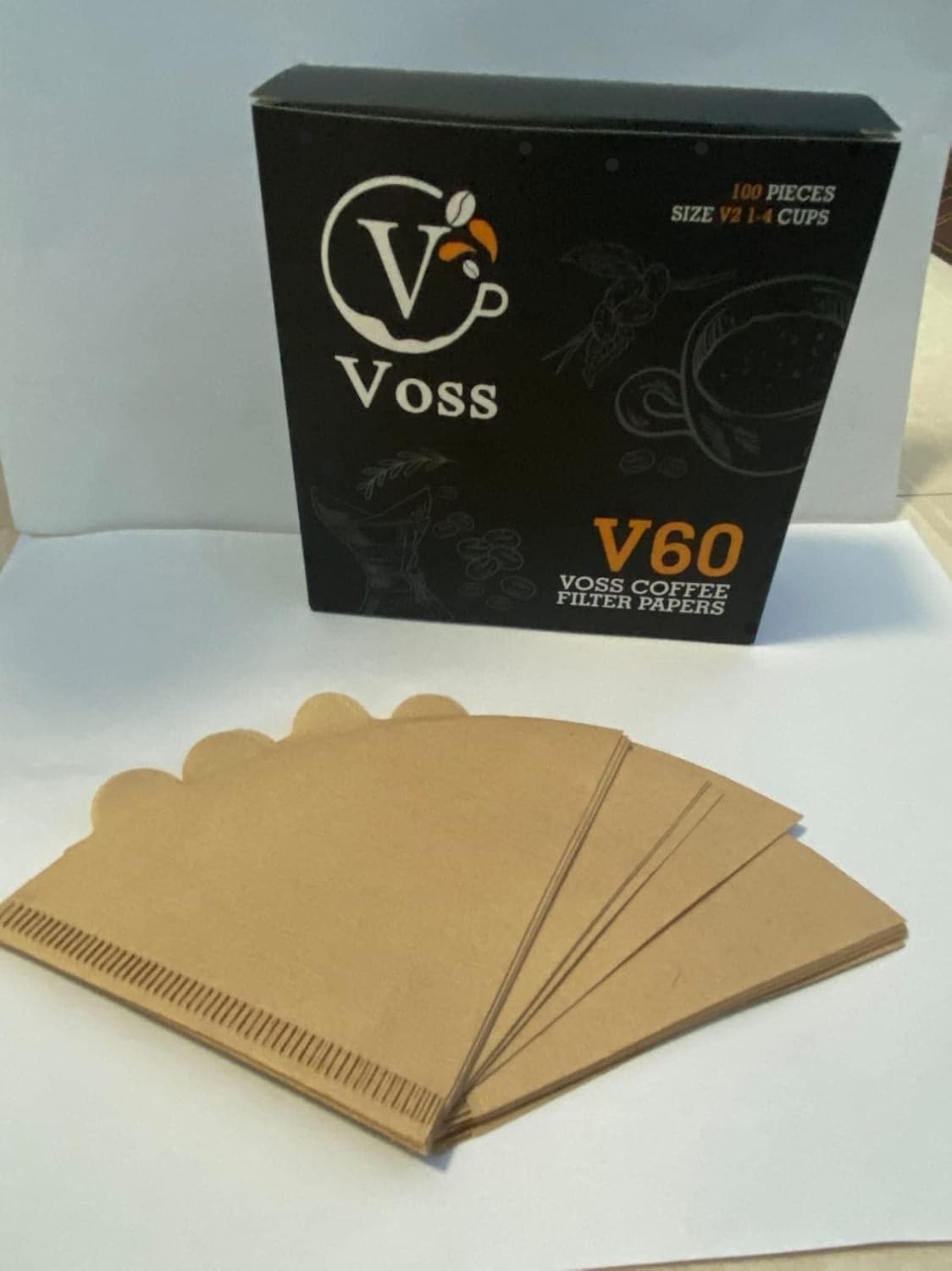 A black box of Coffee Paper Filters, [SIZE] [FILTER TYPE] Coffee Filters, [NUMBER OF FILTERS] Pack, [MATERIAL], Compatible with [COFFEE MAKER / DRIPPER / BREWER], is displayed on a white sheet with four brown, cone-shaped drip coffee filters fanned out in front.